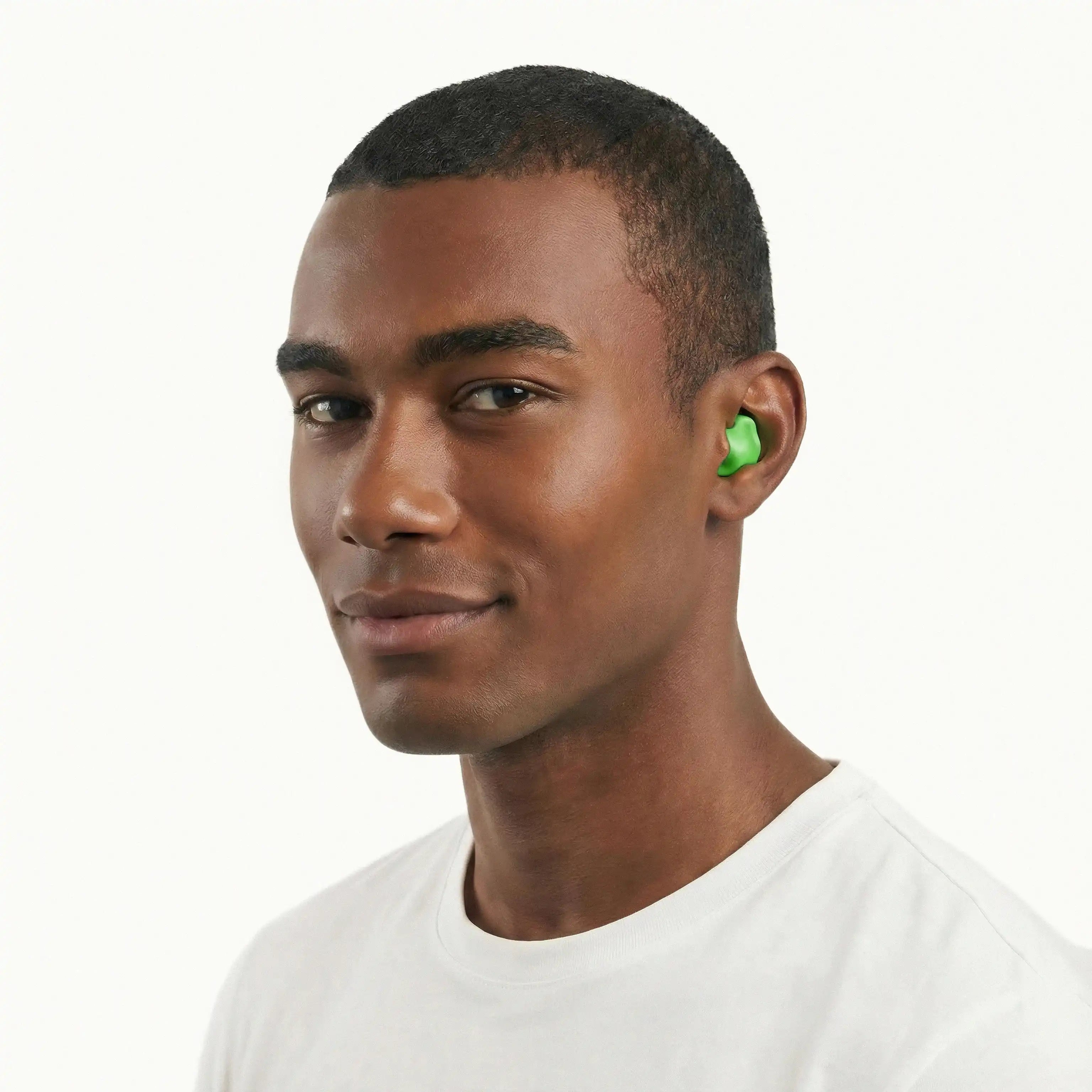 A portrait of a man with short hair wearing a bright green mouldable silicone happy sleep earplug, shown against a clean white background