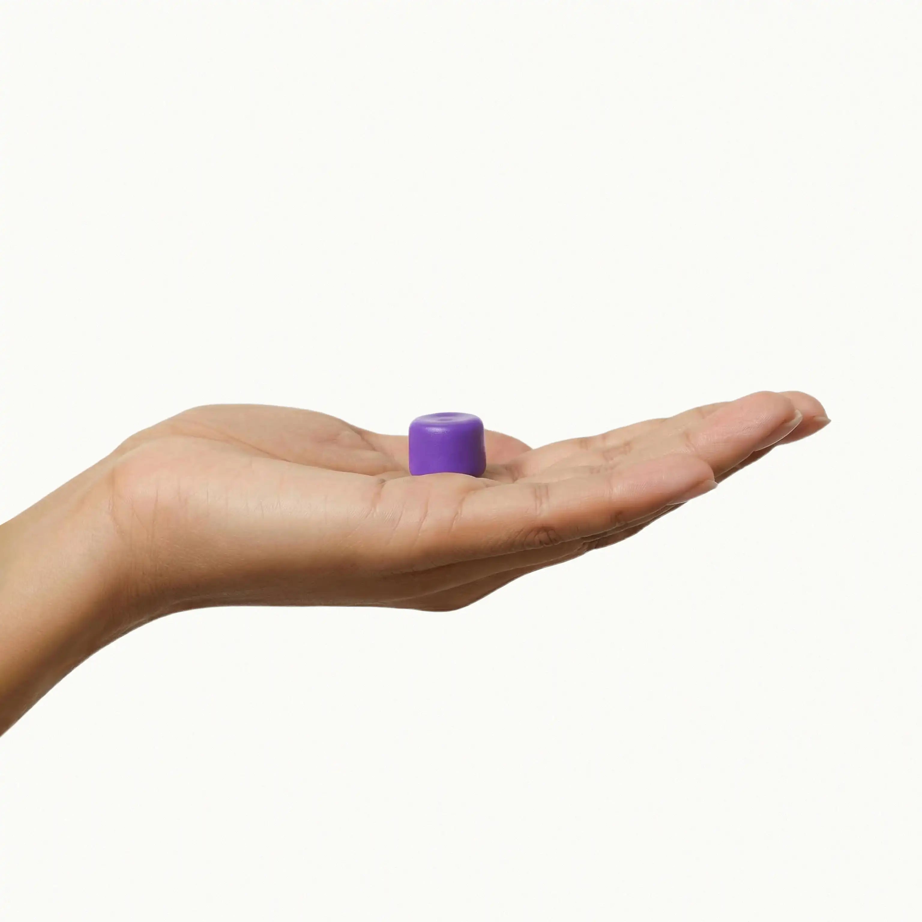 A purple mouldable earplug for noise cancellation and sleep comfort, held in a hand to demonstrate the soft silicone material